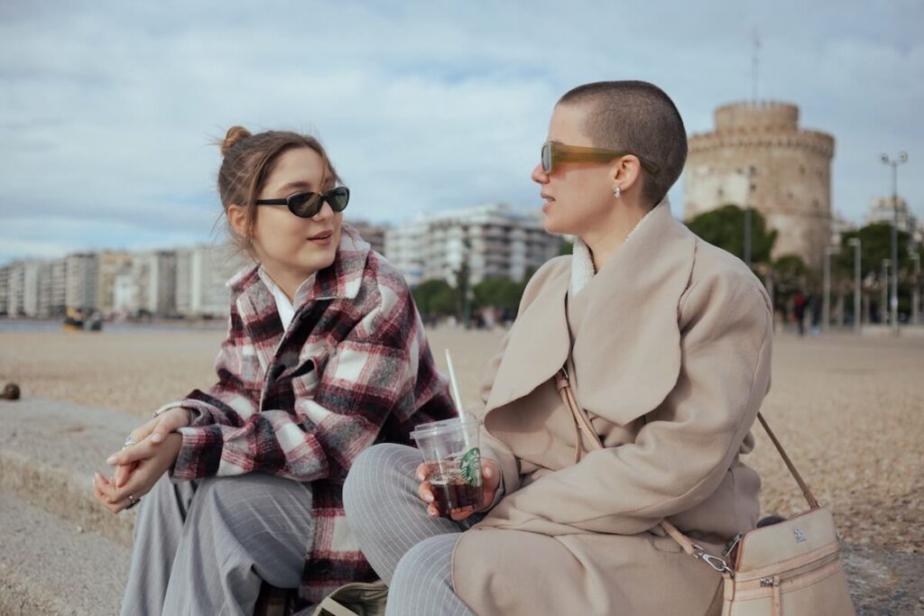 two women talking and sitting by the beach