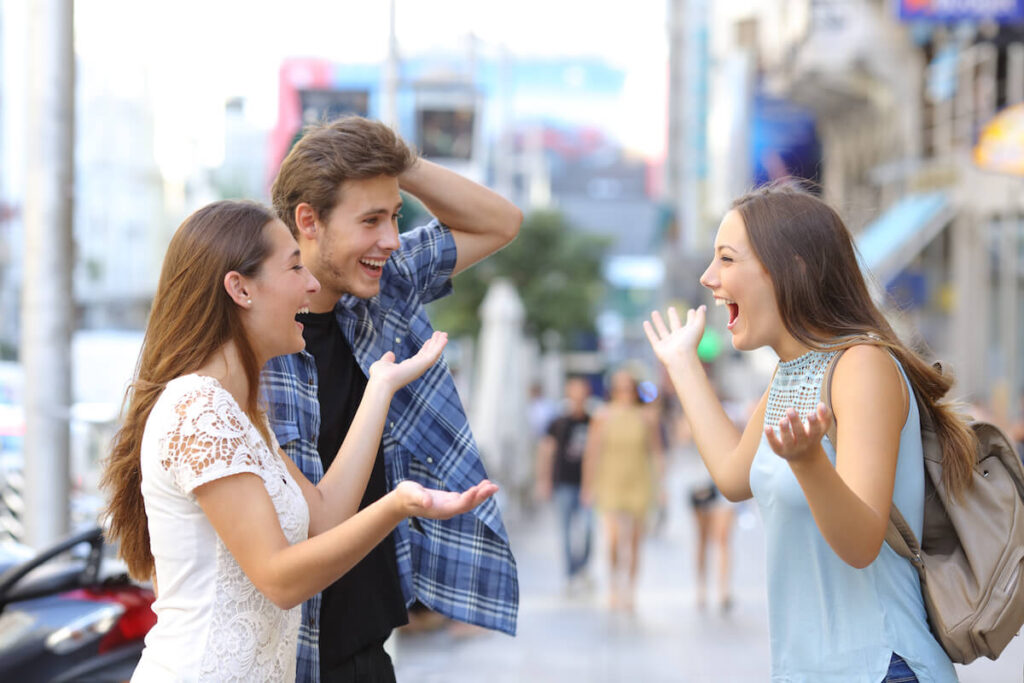 Three happy friends meeting on the sidewalk of a street of a big city with an urban background