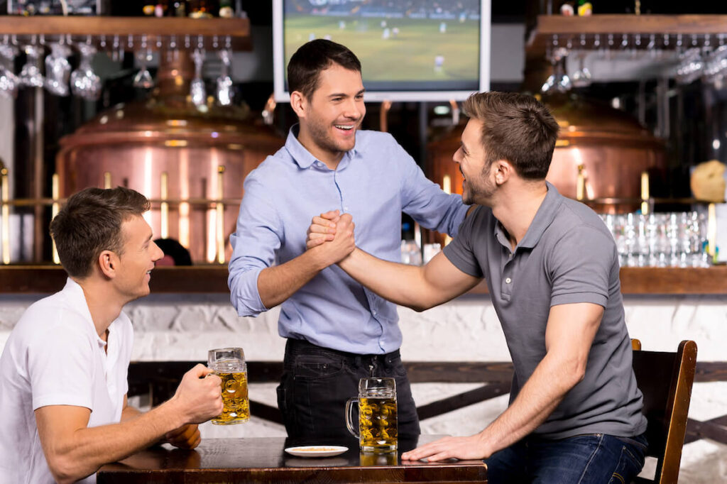 Three cheerful friends meet each other in beer pub