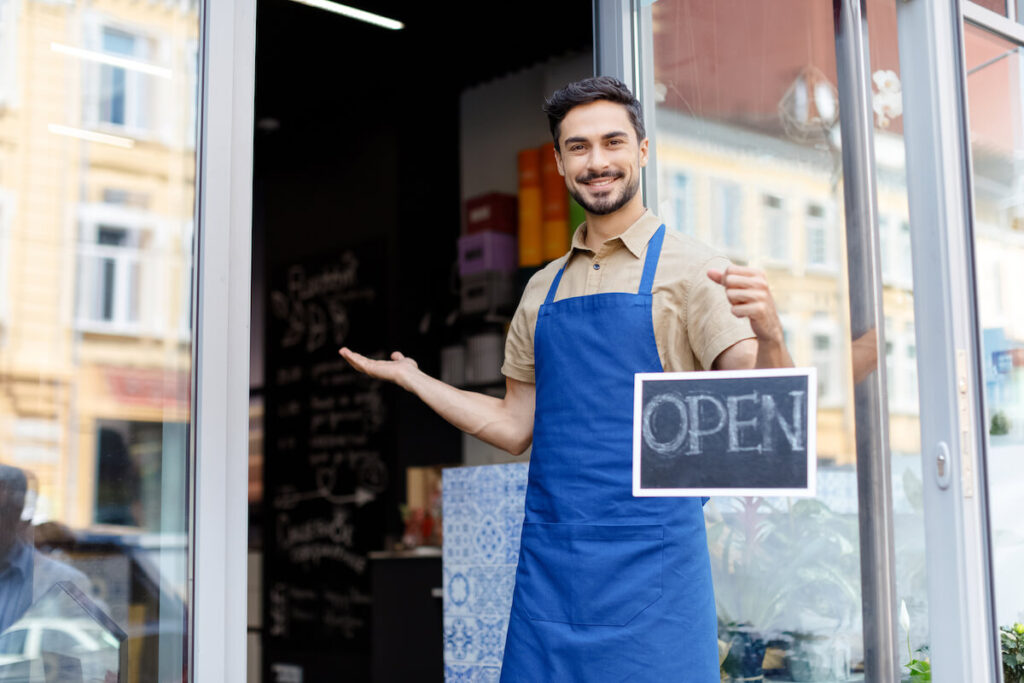 Small business owner welcoming customer with open sign