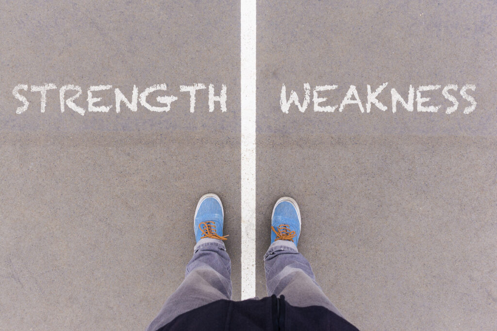 Strength and weakness text on asphalt ground