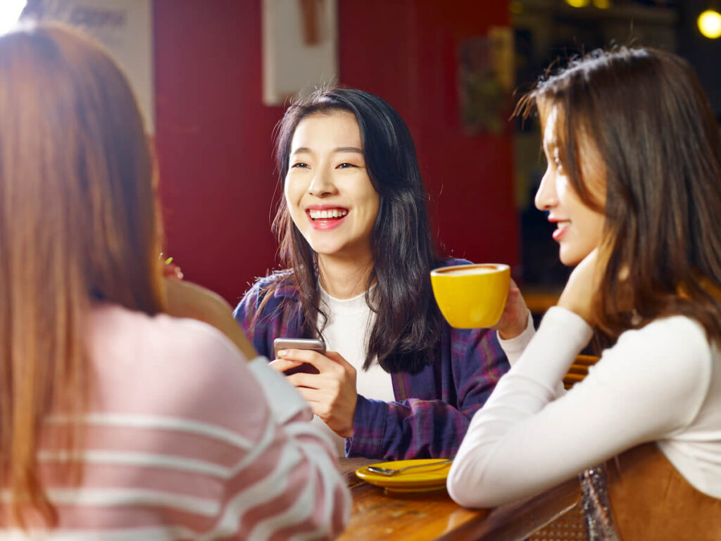happy Asian women talking at a cafe