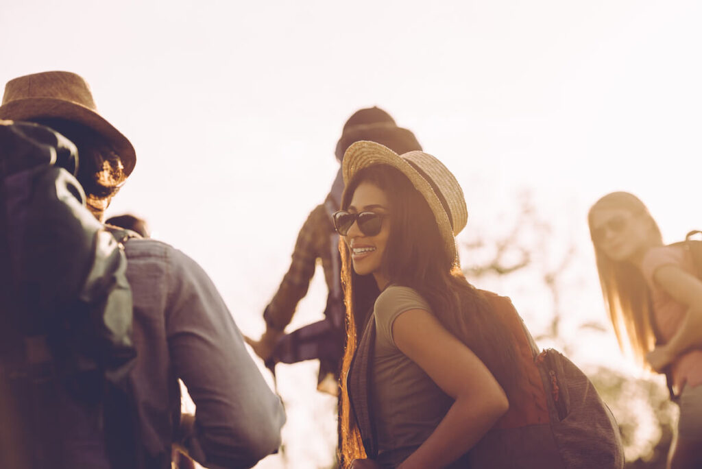 Group of young people with backpacks walking together and looking happy
