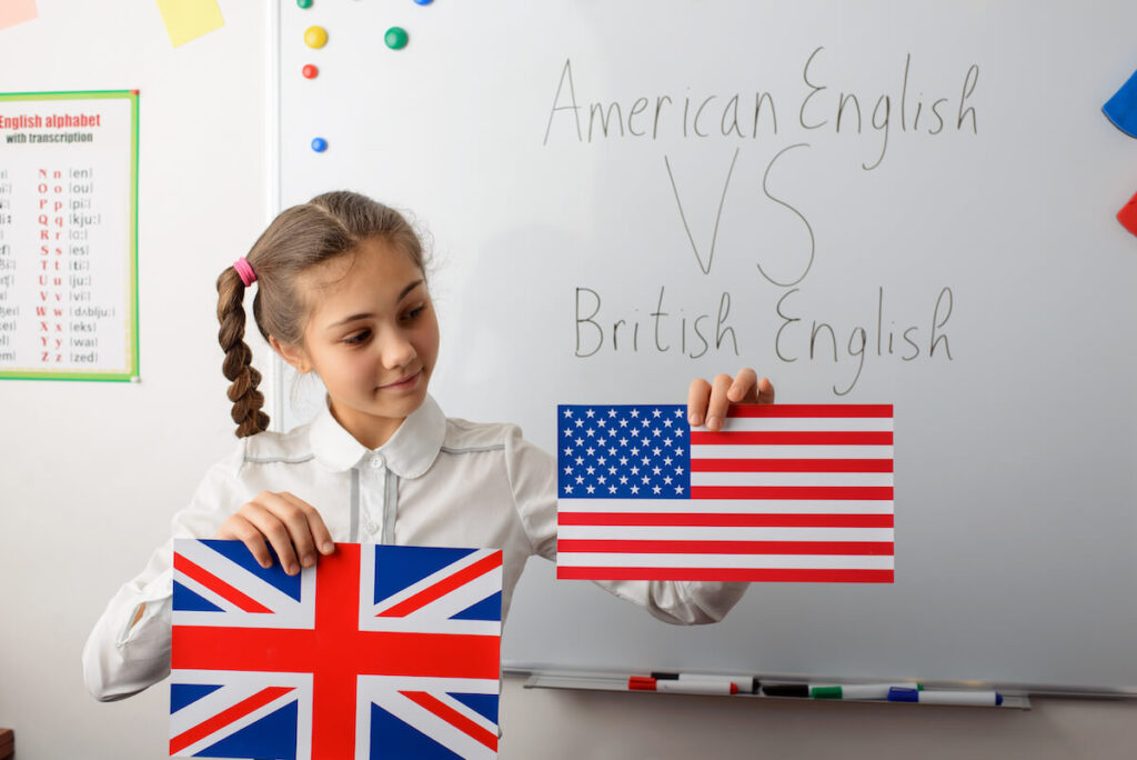 Small school learner girl holding flag of the US and the UK