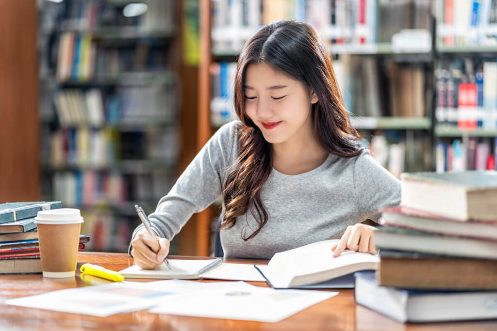 smiling student taking down notes from books