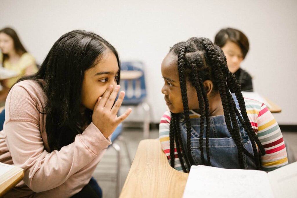 Girls whispering together in classroom