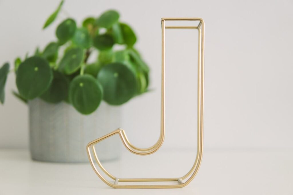 brass colored decorative marquee letter J on table