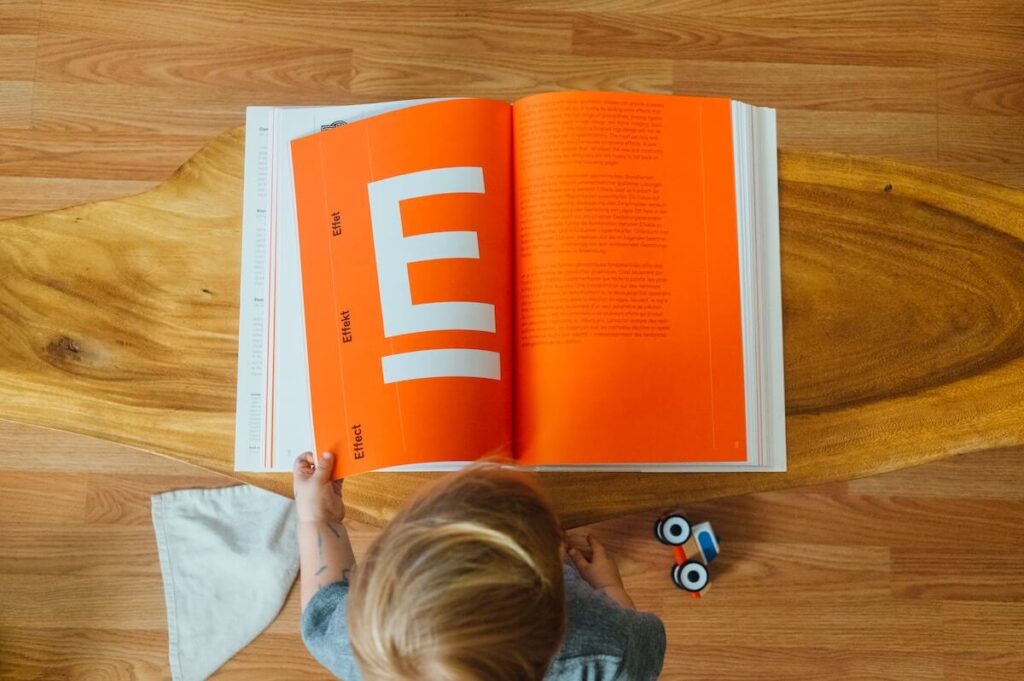 child opens book orange E page