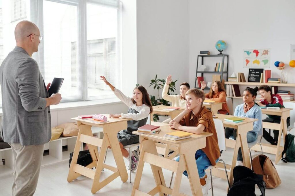 Students at desk raising hands