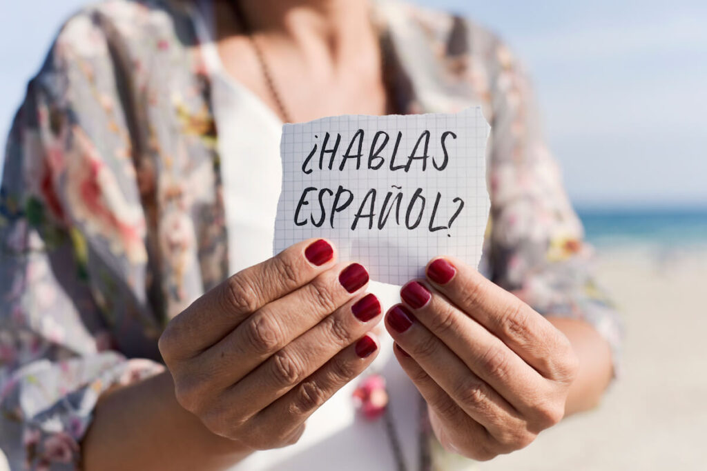 woman holding hablas espanol handwritten note