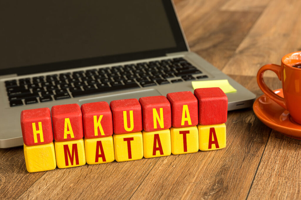 wooden blocks spelling out Hakuna Matata with laptop and mug