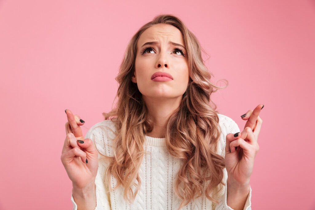 Hopeful young woman with fingers crossed