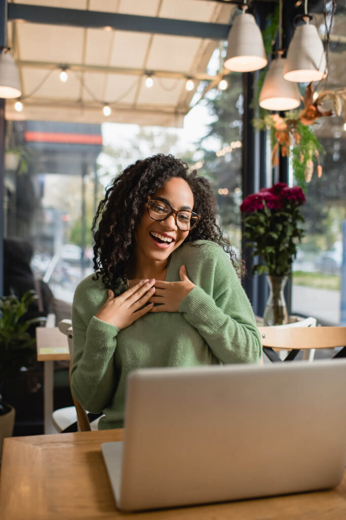 grateful woman in glasses looking at laptop