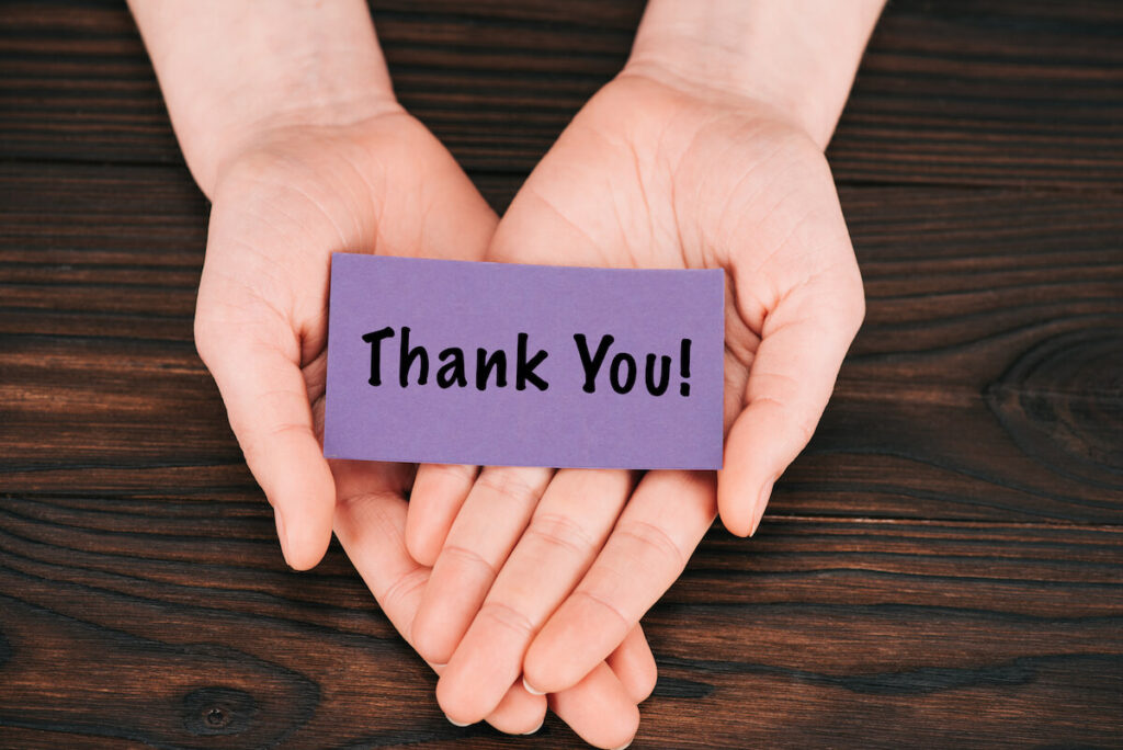Cropped shot of woman holding purple paper with thank you lettering