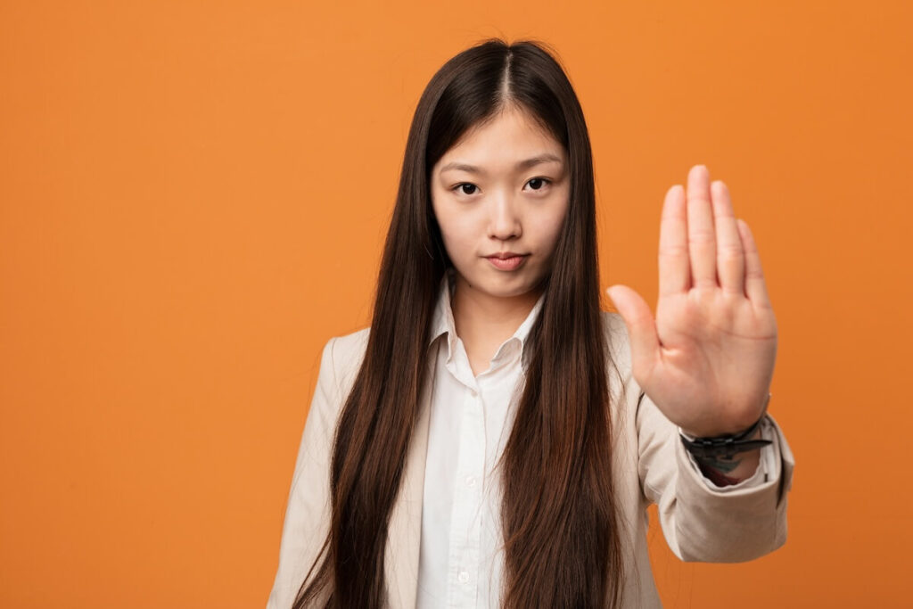 Young businesswoman standing with outstretched hand showing stop sign