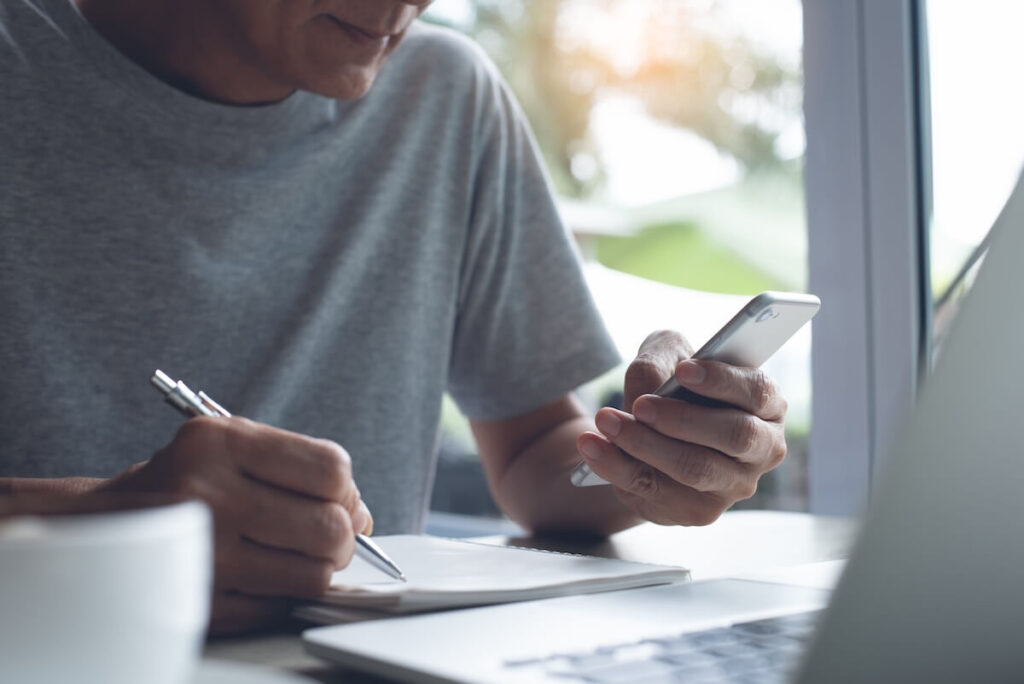 man taking down notes from phone