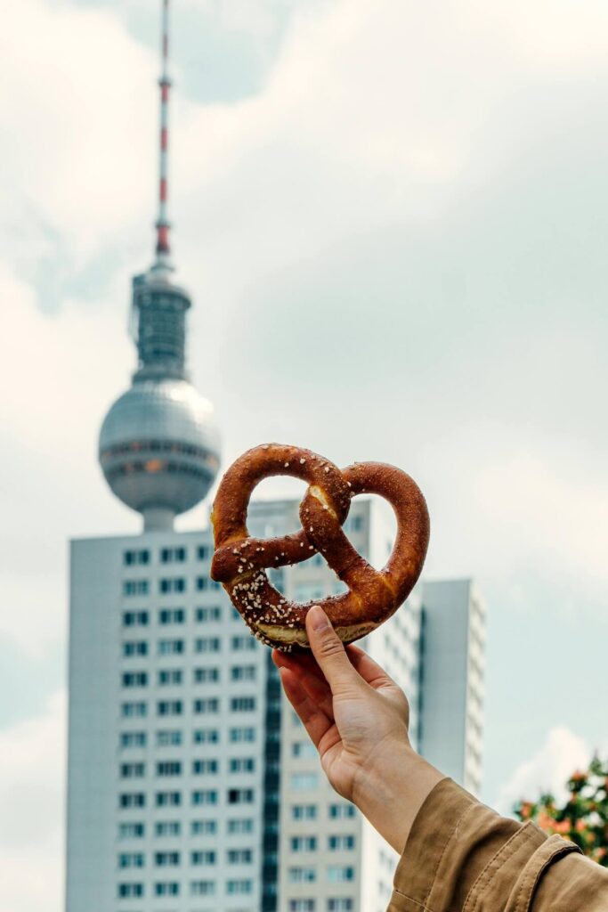 Woman Holding a Pretzel on the foreground of the Fernsehturm Berlin