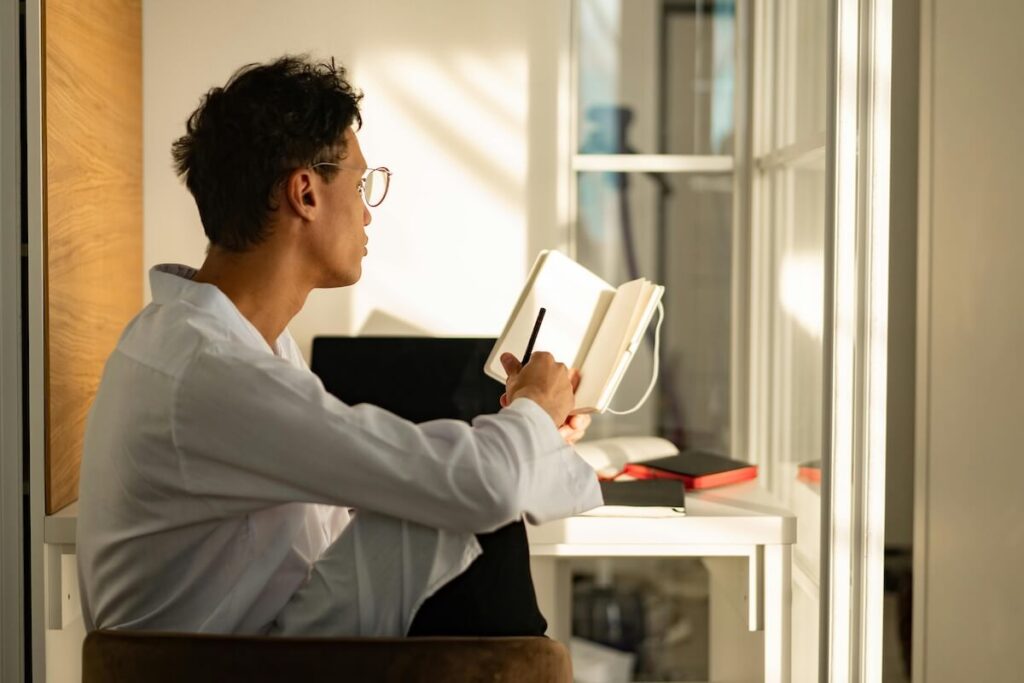man writing down something on notebook