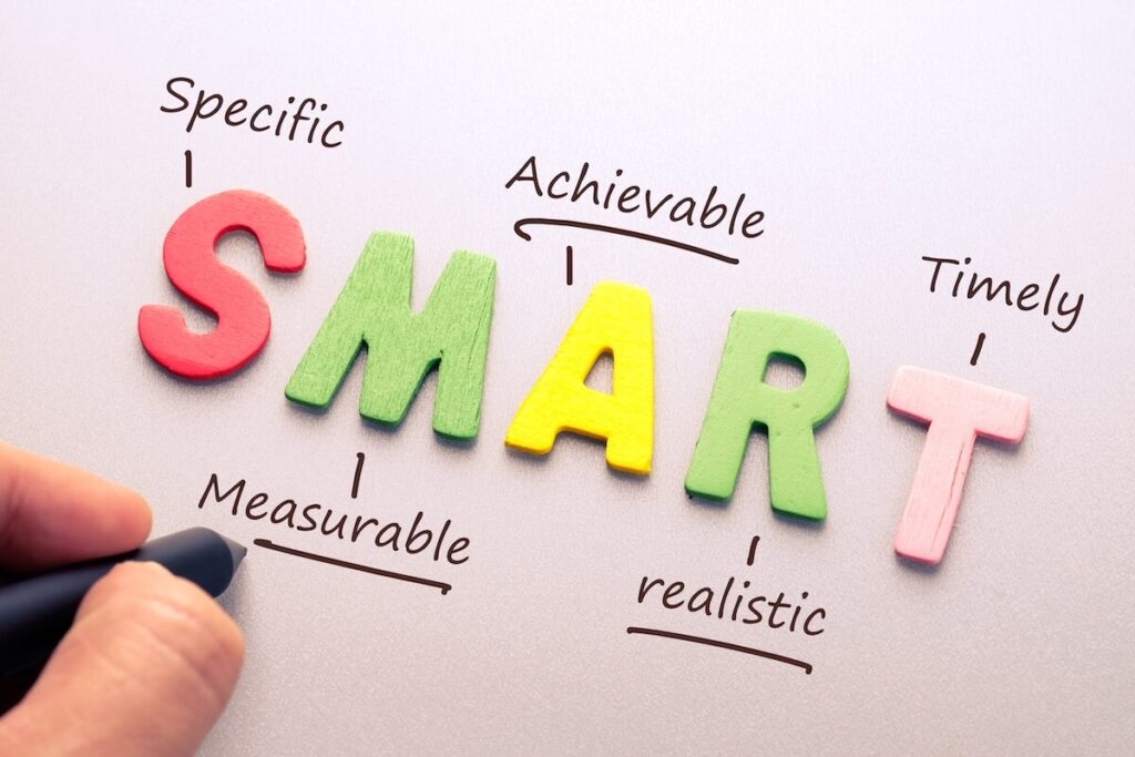 person holding pen writing down SMART goals