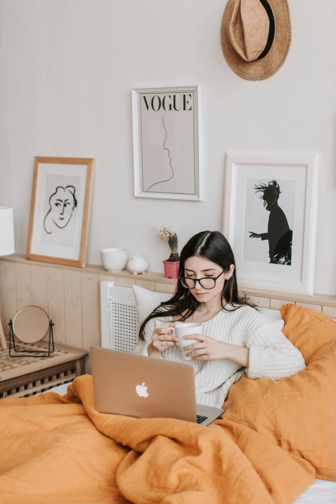 woman cozying up with laptop, drink, and blanket