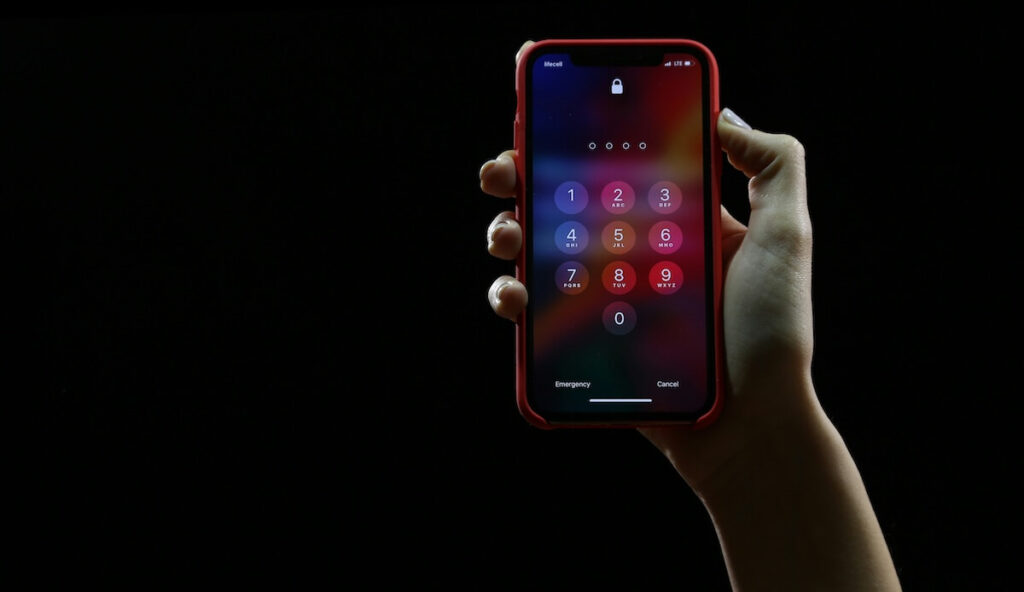 man holding mobile phone with number pad