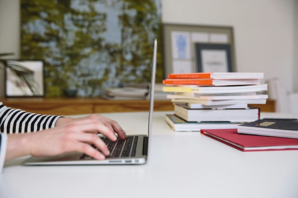 person using laptop and books on desk