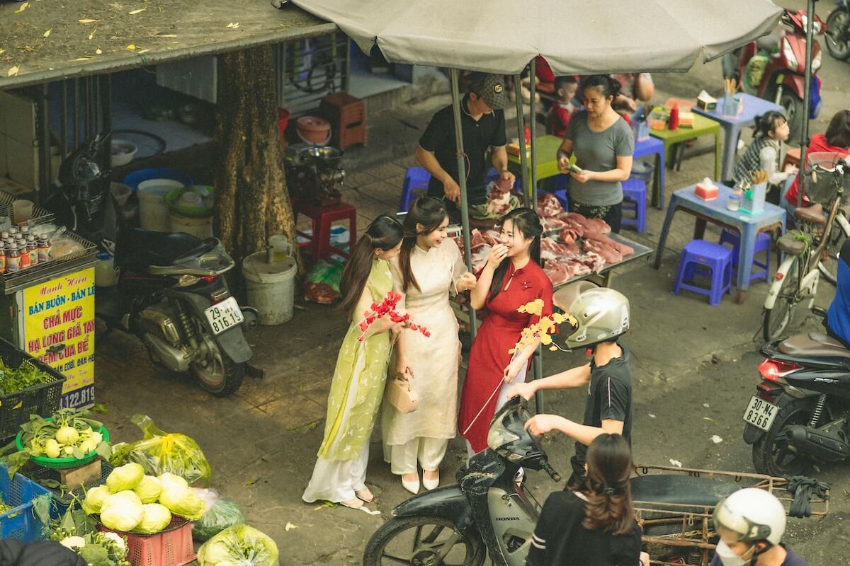 women wearing Ao Dai and talking in market in Vietnam