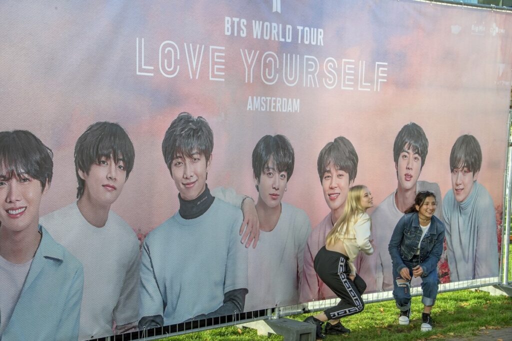 women taking Pictures At A Billboard Before The BTS Concert
