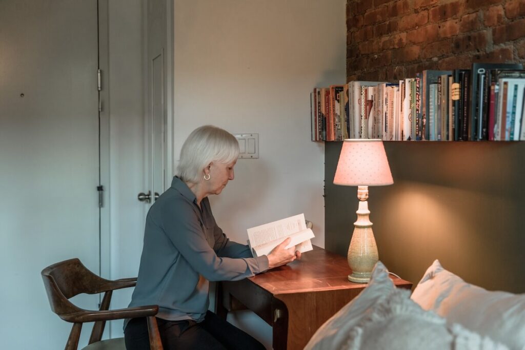 old woman reading a book in desk