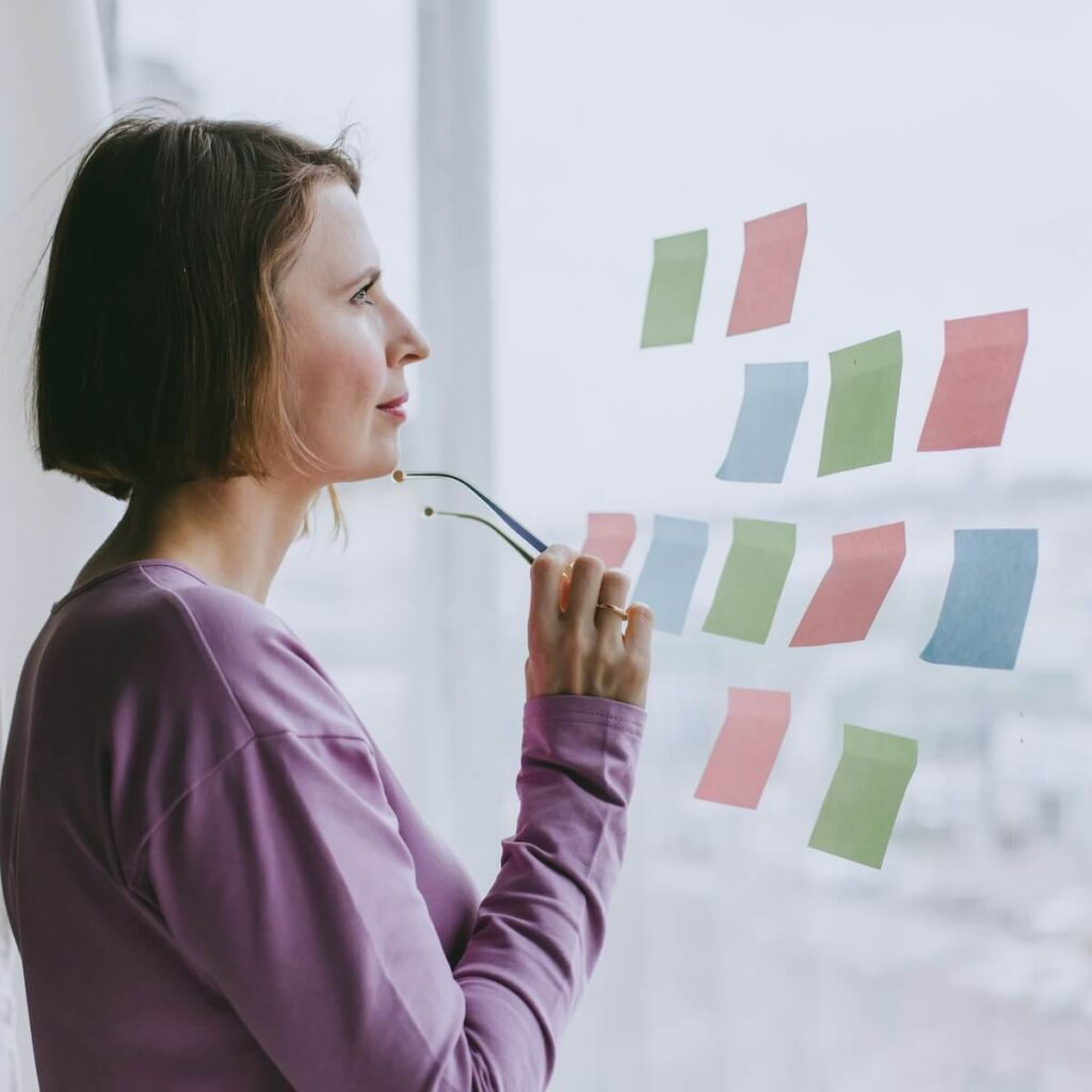woman looking at post-its while thinking and making decision